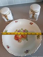 Top view showing 12-inch Bavarian fruit platter with measuring tape across and two white canisters on either side