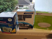 Photo showing the boxed LifeSource blood pressure monitor, Garrison privacy door knob, and 7.5-inch LED flush mount light, all in packaging indicating new condition.