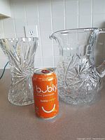 Photo showing both the crystal pitcher and vase side by side with an orange Bubly can for size reference on a kitchen counter.