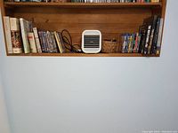 Shelf containing mix of DVDs, Blu-rays, books and a portable air cooler