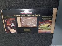 Boxed Himalayan salt cooking brick with plastic-wrapped brick visible through box window and printed cooking instructions on the box sides.