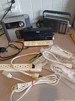 Photo showing two radios and multiple white extension cords/power strips on countertop