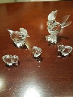 Full set of five Swarovski crystal figurines on wood surface: one rooster, one hen, three chicks.