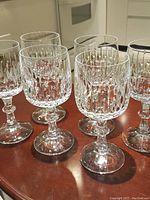 Six crystal wine glasses arranged on a wooden table showing the Flamenco cut pattern.