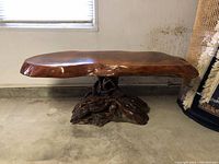 Side view showing the oval burl wood tabletop and natural wood root base.