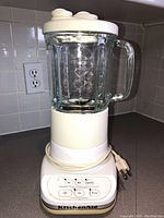 Front view of vintage KitchenAid blender showing glass jar, lid, and base with control buttons and KitchenAid branding.