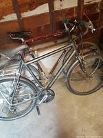 Two vintage men's bikes positioned indoors, KHS Urban Express in foreground with rear and front fenders, rear rack, visible drivetrain and branding on frame