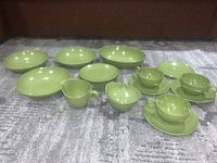 Full set arranged on gray carpet showing all pieces including plates, bowls, cups, saucers, sugar bowl, cream pitcher, and oblong bowl; olive drab green color and mid-century style