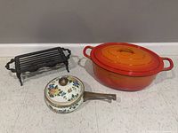 Wide view showing the enameled pan, Dutch oven, and cast iron warming stand.