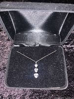 Full view of necklace in black jewelry box on black velvet background