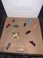 Overview of the bee pin with nine interchangeable wing attachments in different colors displayed in original beige velvety tray inside Joan Rivers Classics Collection box.