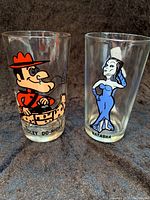 Front view of two Pepsi collector glasses from the 1970s featuring Dudley Do-Right on the left and Natasha on the right, showing vibrant cartoon images and character names.