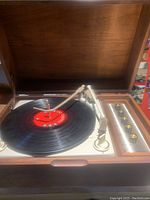 Open wooden case displaying the turntable with a vinyl record on it and tonearm positioned.