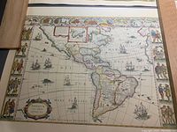 Map print showing detailed map of North and South America with decorative border and sailing ships illustrated on sea.
