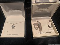 Sterling silver necklace with cubic zirconia pendant displayed in box marked Sterling Silver and Cubic Zirconia; 14K gold over sterling silver earrings with genuine crystals in box marked 14kt gold over sterling silver and Genuine Crystal.