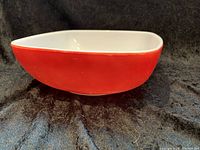 Side view of vintage Pyrex bowl displaying rounded square shape and red exterior.