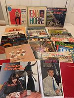 Photo showing a variety of vintage vinyl LP record albums stacked and displayed with visible cover art including Chubby Checker, Lena Horne, Beach Boys, Dionne Warwick, and various others.