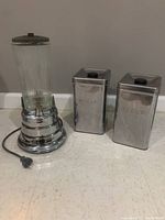 Full view of Waring blender with glass jar and two stainless steel canisters labeled Sugar and Flour