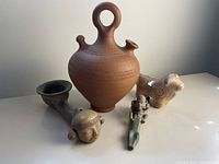 Four pieces of Mexican pottery shown together: the jug, bull figure, and two clay pipes