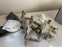 Photo showing antique brass taps, connectors, and fittings arranged on a table.