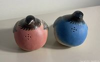 Front view of blue and pink ceramic bird salt and pepper shakers showing dispensing holes on top.