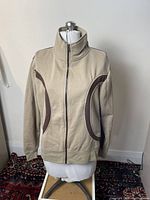 Front view of the large tan sports jumper with brown side panels and zip-up collar