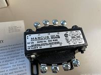 Close-up of Marcus M050B control transformer showing label with voltage, frequency, catalog number and terminal markings.