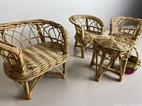 Close up showing three wicker chairs and a round table, highlighting the weaving and construction details of the toy furniture set