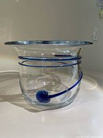 Front view of clear glass bowl showing blue swirl and small blue orb inside body. Broad flared rim and rounded base visible.