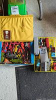 Top-down view of yellow carrying case filled with assorted toy cars and trucks, including a small organizer tray with more vehicles.