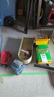 Green and yellow toy truck with dumper bed and black plow attachment, paired with small red metal wagon and blue truck cab.