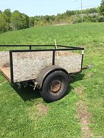 Side view of the utility trailer showing wooden side panels, metal frame, and a tire.