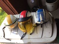 Front view of the three vintage helmets arranged side by side showing colors and visors.