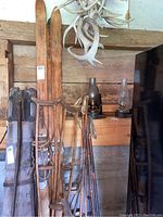 Overall view of vintage skis, poles, crutches, lanterns and some props hanging on wooden wall.