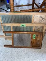 Three vintage washboards displayed together, two with ribbed glass boards and one smaller with tin board marked with sizes.
