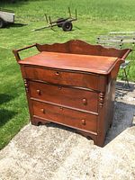 Front view of the antique 3 drawer washstand showing drawer fronts and scalloped backboard with side towel bars.