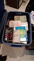 Bin of various paperback books including Games People Play, Tao of Relationships, and The Dragon Doesn't Live Here Anymore, viewed from above