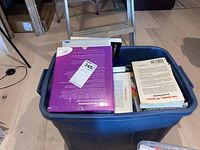 Bin of mixed hard and soft cover books with visible titles including Dragon NaturallySpeaking 6.