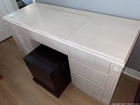 Full view of the off-white manufactured wood desk with six drawers and a closed flip-top center panel.
