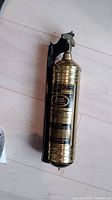 Full side view of brass Pyrene fire extinguisher with black mounting bracket visible in photo.