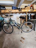 Full side profile of the green Arashi bike showing 26-inch wheels, frame design, seat, and handlebars in a garage setting