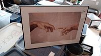 Framed poster showing two hands almost touching in Michelangelo's The Creation of Adam artwork.