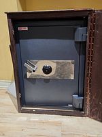 Front view of USCAN Total Security safe inside wooden cabinet with door open, showing combination lock and handle.