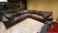 Whole sectional couch arranged in corner, showing all three pieces and four pillows.