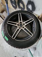Top view of tire and rim showing 5-spoke alloy rim design with black and silver finish and tire tread.