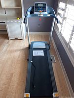 Full view of the treadmill showing the running belt, frame, and user manual placed on the belt.