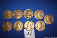 Top view of the nine bronze medallions with presidential profiles clearly visible, arranged on a blue surface with a label showing number '27'.