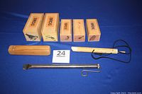 Full set of eight bird calls with five wooden boxed calls, one wooden loon flute, one unidentified wooden call, one metal flute shown on blue surface.