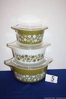 Three nesting bowls stacked with clear lids, displaying Spring Blossom Green pattern