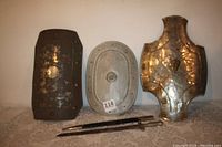 All three shields displayed front-facing with the sword and sheath in front